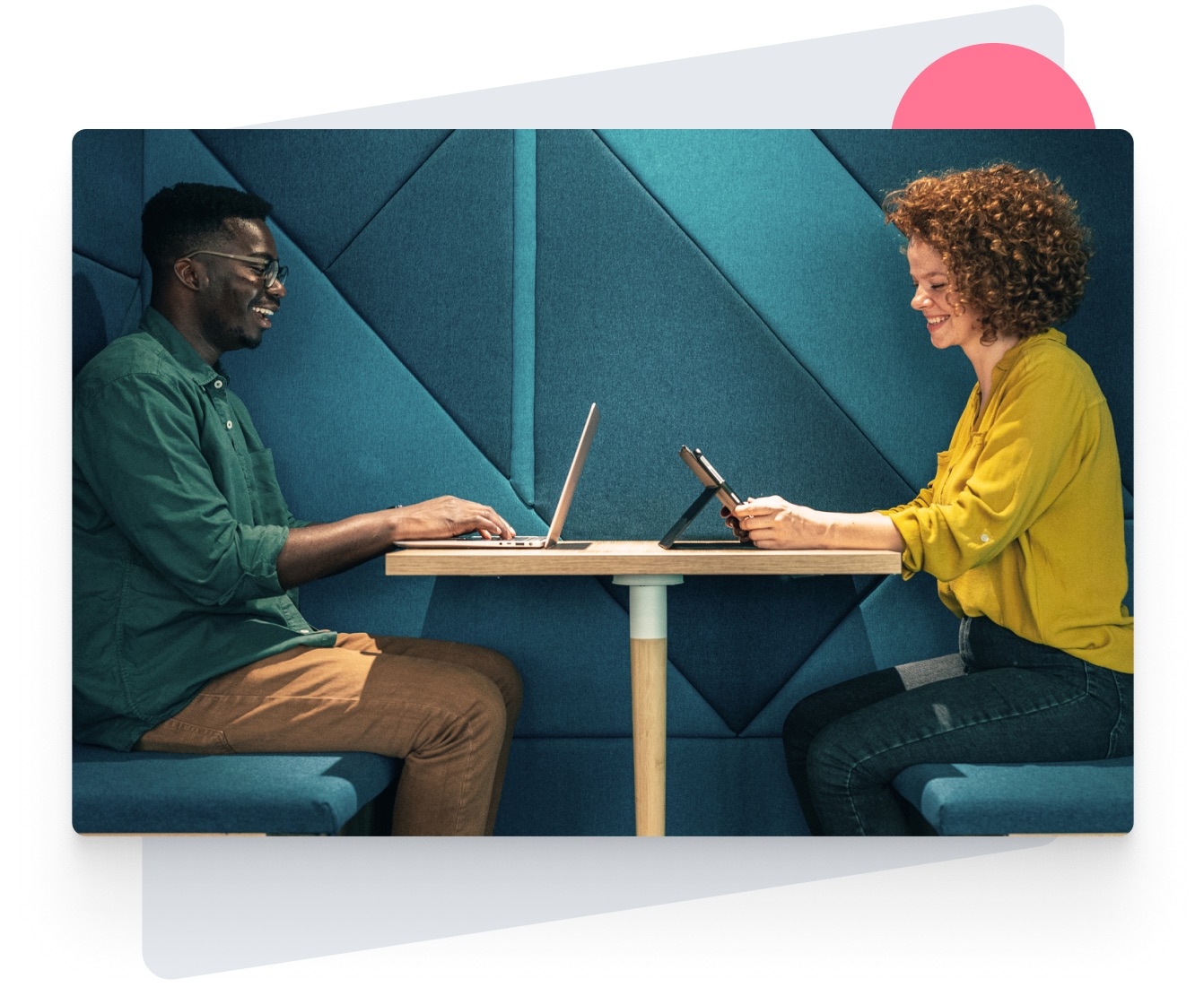 Man with laptop and woman with iPad both smiling and sitting at a table using District Intranet